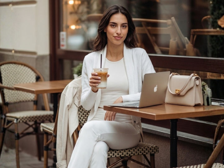 Ragazza seduta al tavolino di un bar con outfit BeGood e coprispalle, look casual e moderno.